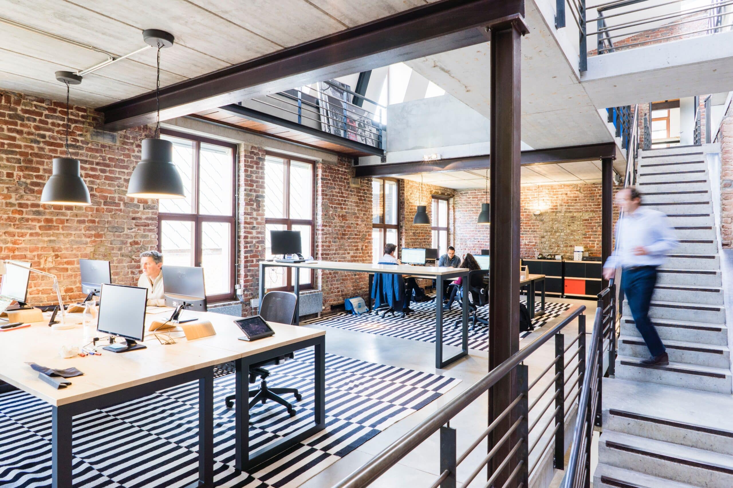 Commercial open-plan office interior with exposed ceiling and suspended lighting